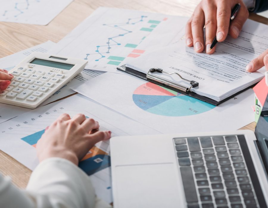 partial-view-of-man-studying-loan-agreement-and-businesswoman-using-calculator-while-sitting-at.jpg